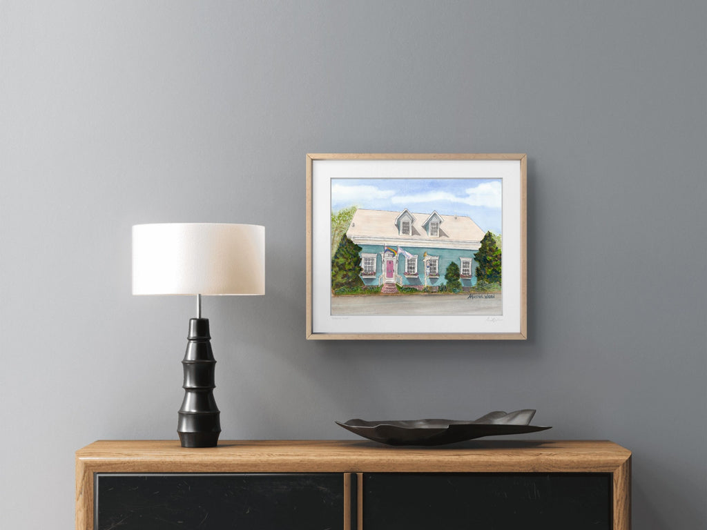 A lifestyle photograph of a maple framed watercolor print above a buffet titled "Admirals Pride" signed by artist Marshal Walden