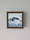 Front view of Emergence, a minimalist monochrome watercolor study of a coastal home, isolated within a deep light walnut float mount frame on a neutral wall.