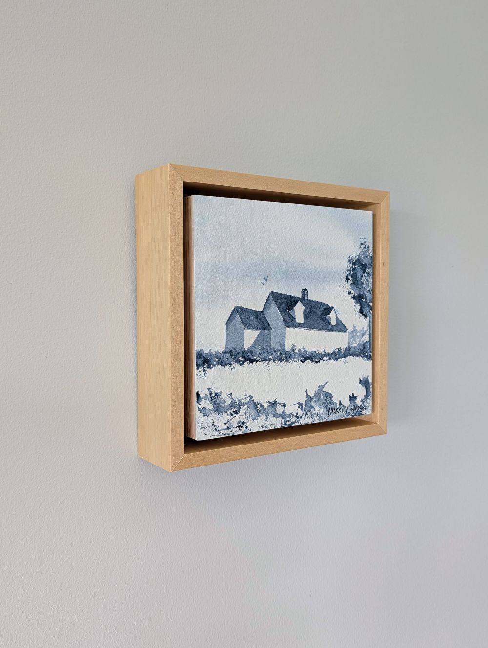 Left side view of Presence, a minimalist monochrome watercolor study of a coastal home, isolated within a deep natural maple float mount frame on a neutral wall.