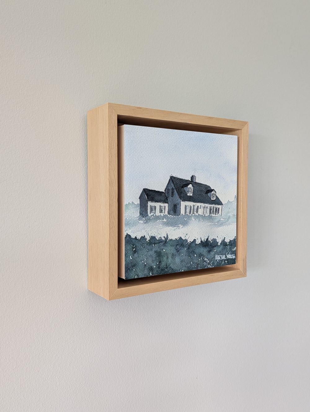Left side view of Witness, a minimalist monochrome watercolor study of a coastal home, isolated within a deep natural maple float mount frame on a neutral wall.