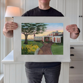 A photograph of artist Marshal Walden holding the large limited edition fine art print "Red Inn Summer Glow." The image demonstrates the scale of the artwork relative to the artist and highlights the detailed watercolor texture of the iconic Provincetown inn bathed in warm summer light. The extra-wide crisp white borders are clearly visible, indicating its versatility for framing—either presented without a mat for a modern aesthetic or matted to a standard 11x14 opening for a traditional presentation.
