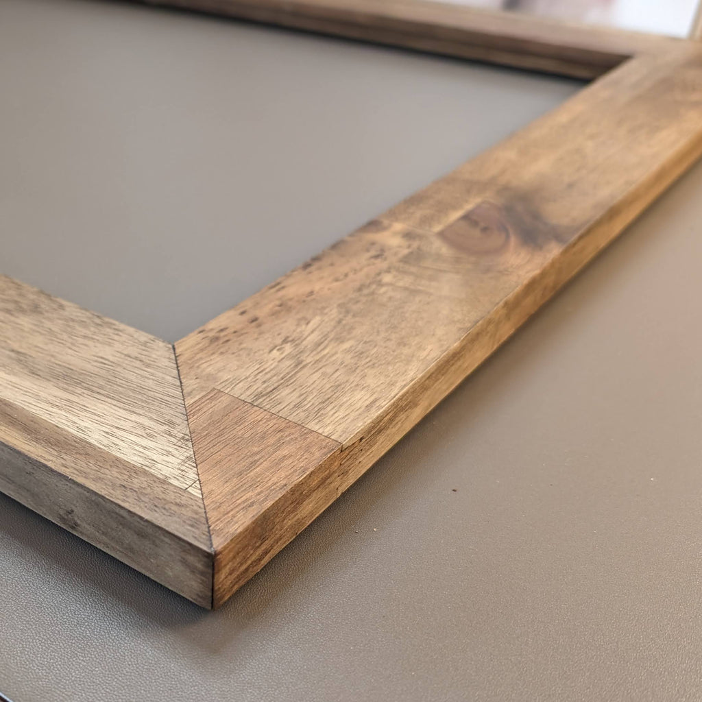 A close-up photograph showing the detailed wood grain and texture of a natural wood art frame from Curbing Art.