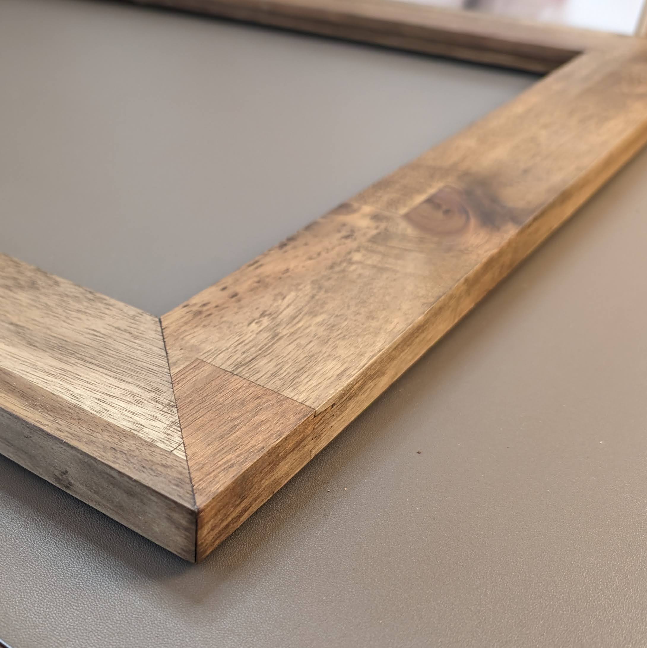 A close-up photograph showing the detailed wood grain and texture of a natural wood art frame from Curbing Art.