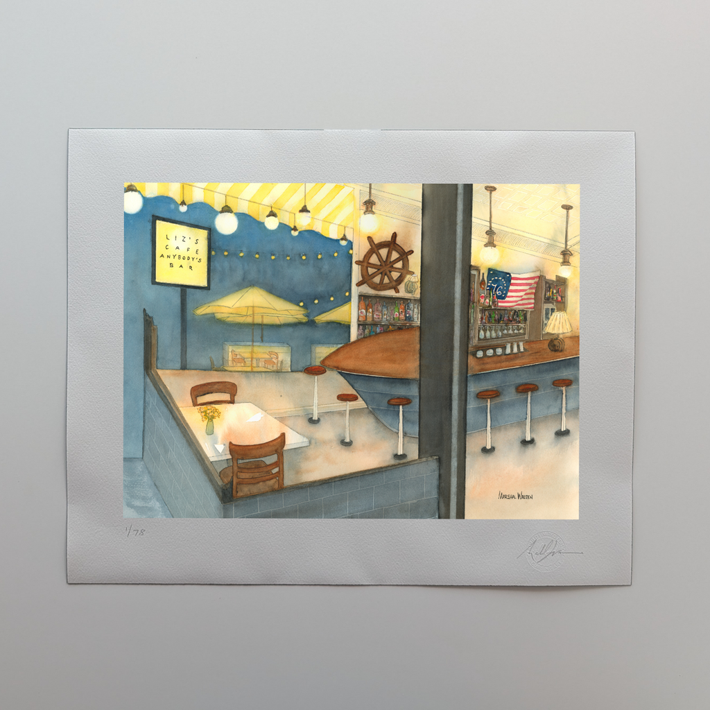A photograph of a 16x20 limited edition fine art print titled "Anybody's Bar" by PAAM member artist Marshal Walden, resting on an off-white tabletop. The watercolor artwork depicts the warm, glowing interior of a bar in Provincetown at night, featuring a unique boat-shaped bar and a ship's wheel, contrasting with a deep indigo summer evening sky visible through the windows. The wide white border of the print displays the artist's hand-penciled signature, the edition numbering out of 78, and the official "Cu