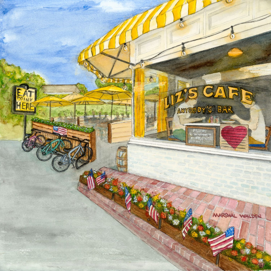 A high-resolution close-up photograph showcasing the intricate details and fine art paper texture of the limited edition print "Window With A View" by PAAM member artist Marshal Walden. The image highlights the detailed watercolor brushwork of Liz's Café (Anybody's Bar) in Provincetown, featuring its iconic bright yellow umbrellas, vibrant flower boxes with American flags, and large picture windows along Bradford Street. The signature "Marshal Walden" is visible in the bottom right corner of the artwork.
