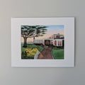 A professionally printed fine art watercolor open edition titled "Red Inn Summer Glow", hand-titled and signed by artist Marshal Walden, centered against a neutral beige wall. The artwork captures the iconic Provincetown building bathed in warm summer sunset light, casting long, deep shadows that emphasize its architectural form.

