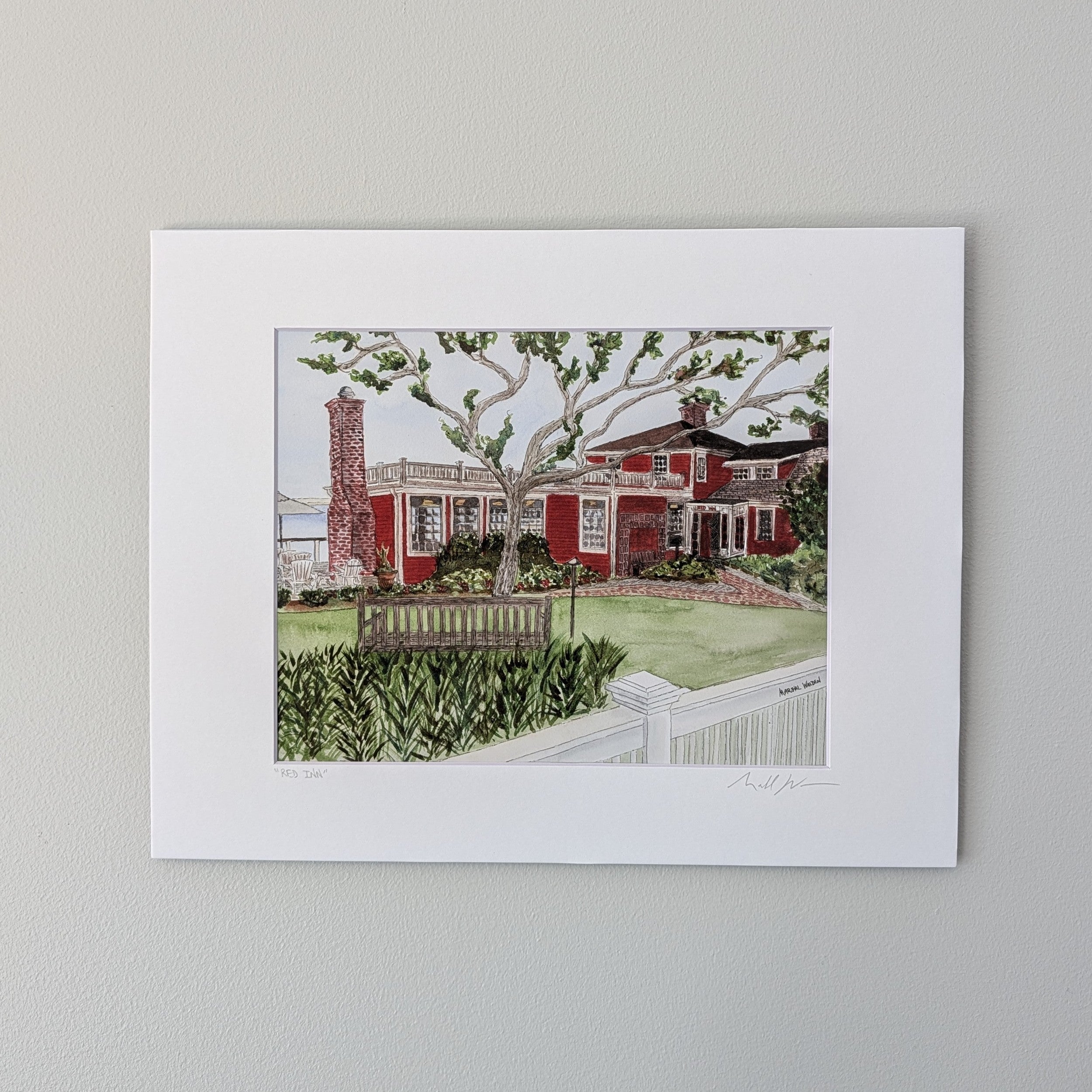 A professionally matted fine art watercolor print titled "The Red Inn", titled and signed by PAAM artist Marshal Walden on the matting. The artwork captures the iconic red landmark in Provincetown, focusing on its structural bones and architectural beauty, displayed centered against a neutral beige wall.
