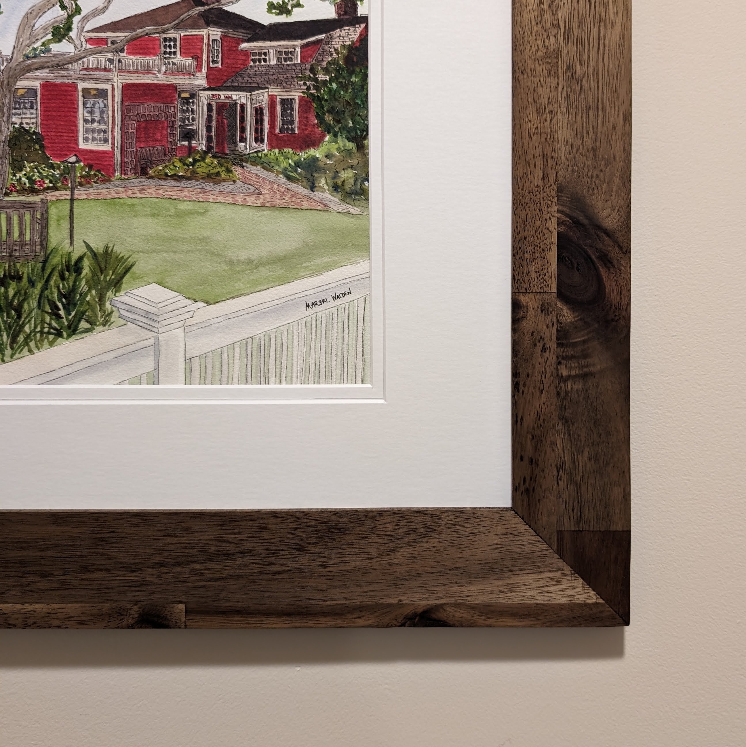 A framed original watercolor painting of The Red Inn in Provincetown, housed in a natural wood frame with a double white mat.