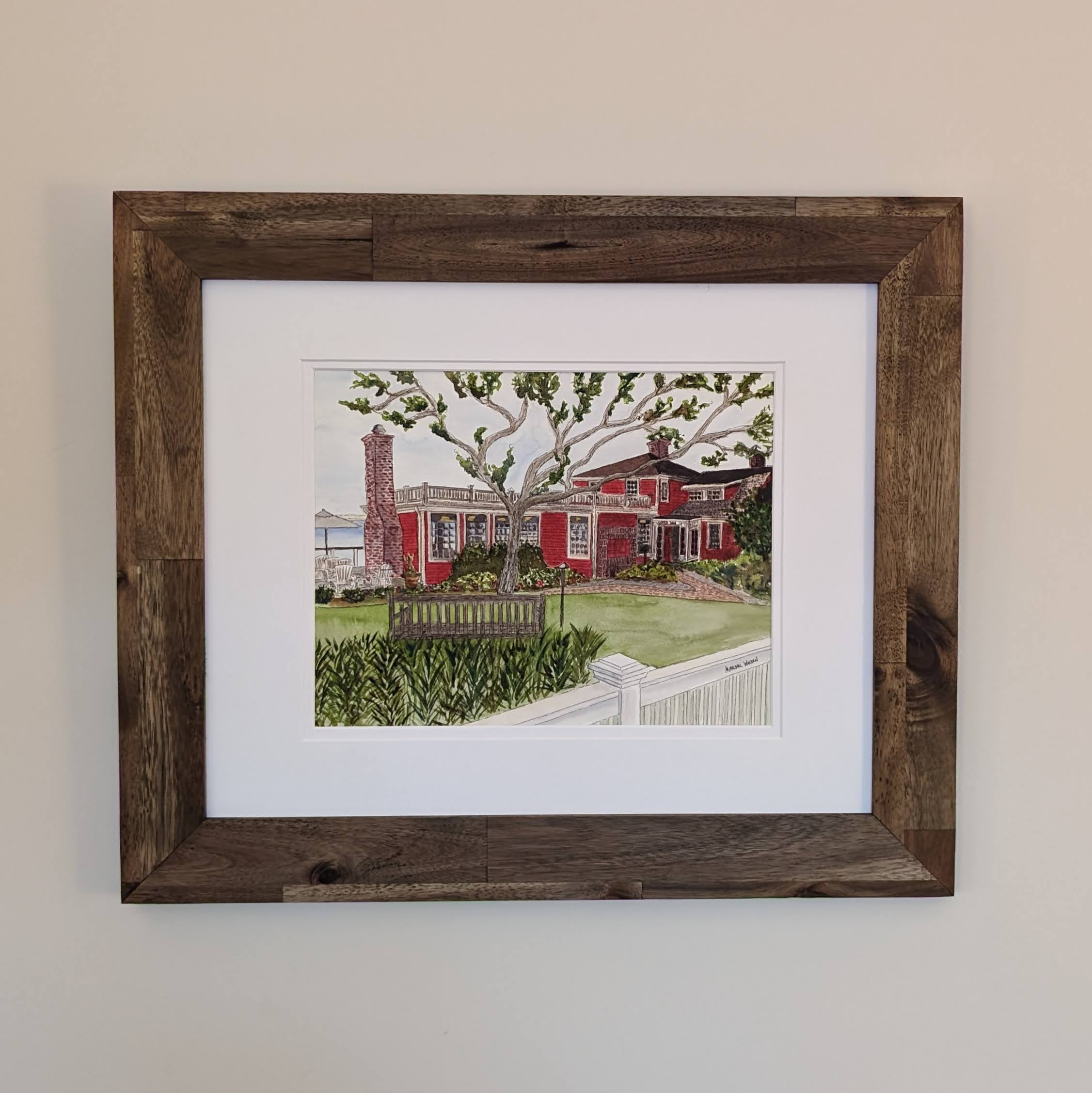 A framed original watercolor painting of The Red Inn in Provincetown, housed in a natural wood frame with a double white mat.
