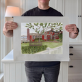 A photograph of artist Marshal Walden holding the large limited edition fine art print "Red Inn." The image demonstrates the scale of the artwork relative to the artist and highlights the detailed watercolor texture of the iconic red building situated on the Provincetown waterfront. The extra-wide crisp white borders are clearly visible, indicating its versatility for framing—either presented without a mat for a modern aesthetic or matted to a standard 11x14 opening for a traditional presentation.
